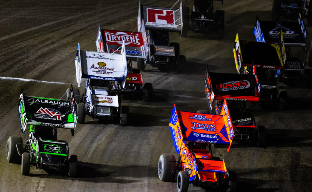 A pack of World of Outlaws Sprint Cars take the green flag out of Turn 4
