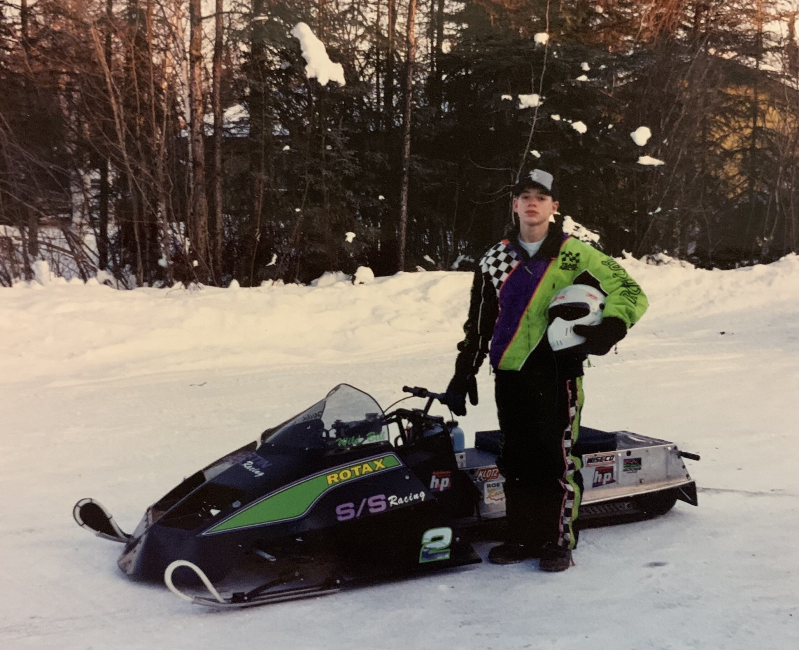 A young Bill Balog stands in front of his snowmobile