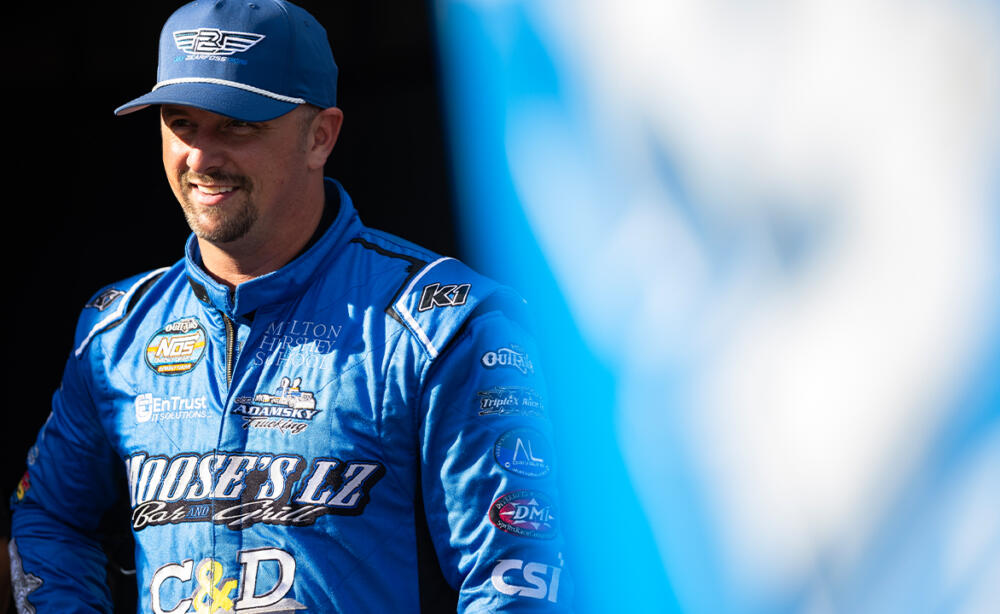 Brock Zearfoss stands smiling in front of his Sprint Car