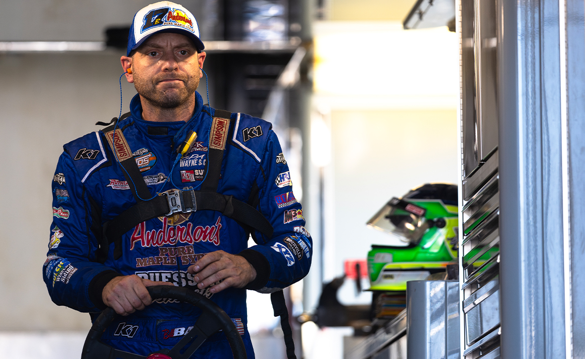 Bill Balog stands in his trailer holding his steering wheel