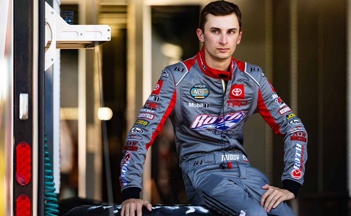 Buddy Kofoid sits on a Hoosier tire in his fire suit.