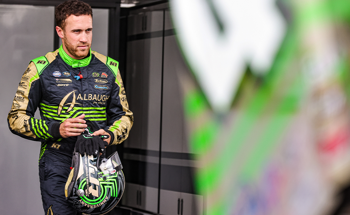 Carson Macedo in his fire suit holding his helmet